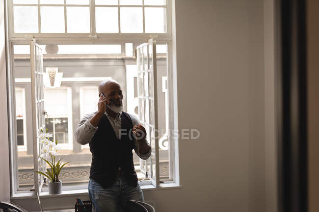 Старший графічний дизайнер розмовляє на мобільному телефоні в офісі — стокове фото