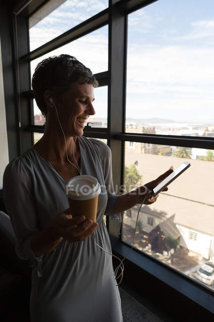 Reife Geschäftsfrau lächelt mit Handy im Büro — Stockfoto