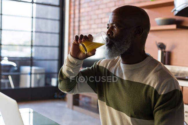 Close-up de homem sênior tomando suco em casa — Fotografia de Stock