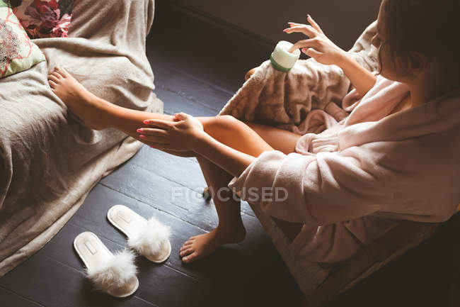 Молода жінка застосовує лосьйон для тіла вдома — стокове фото
