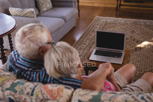 Romantic senior couple sitting on sofa in living room at home — Stock Photo