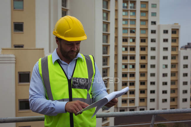 Architect checking documents on clipboard at site — Stock Photo