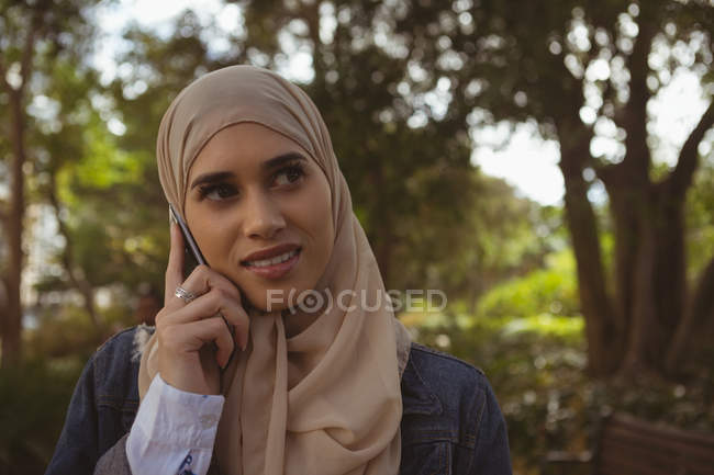 Hermosa mujer hijab hablando en el teléfono móvil en el jardín - foto de stock