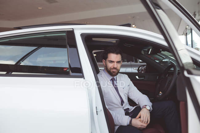 Retrato del vendedor seguro sentado dentro del coche - foto de stock