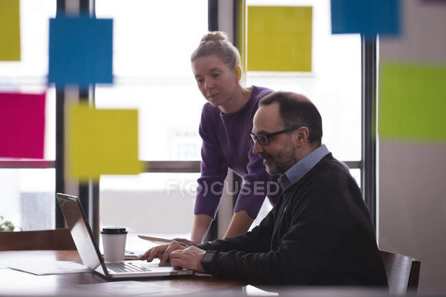 Бізнес-колеги, що працюють на ноутбуці за столом в офісі — стокове фото
