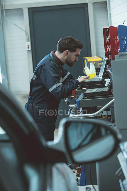 Mécanicien attentif en utilisant un ordinateur portable dans le garage de réparation — Photo de stock
