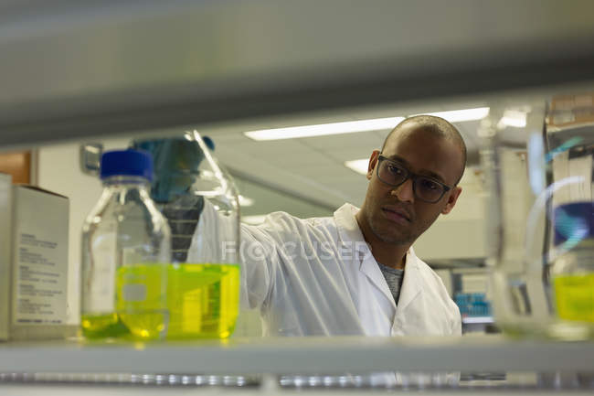 Scientifique vérifiant une solution dans une fiole conique en laboratoire — Photo de stock