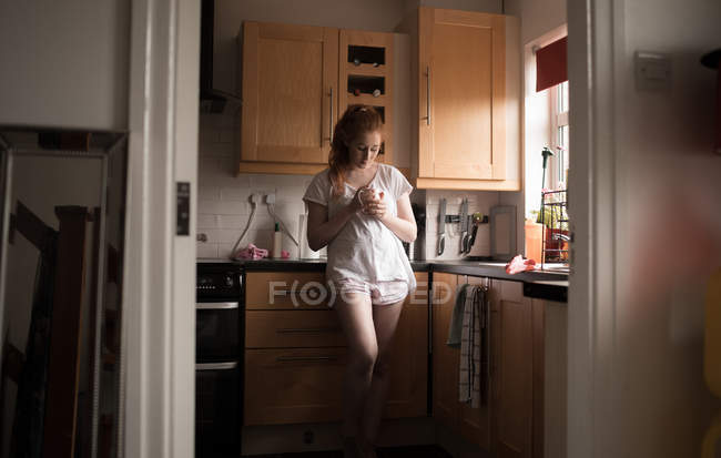 Задумчивая женщина пьет кофе на кухне дома — стоковое фото