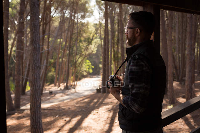 Side view of man with vintage camera standing at cabin porch — Stock Photo