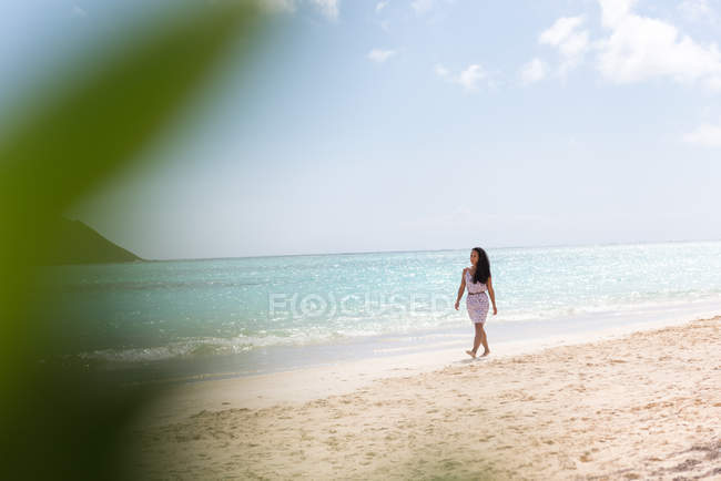 Mujer caminando sola en la playa en un día soleado - foto de stock