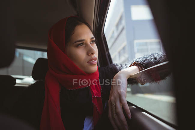 Beautiful hijab woman looking through car window — Stock Photo