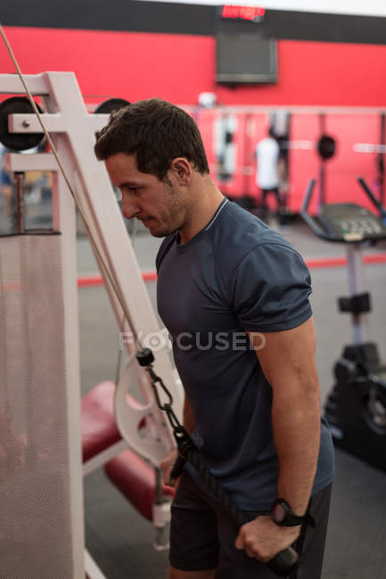 Seitenansicht des Mannes beim Training mit Trainingsgeräten im Fitnessstudio — Stockfoto