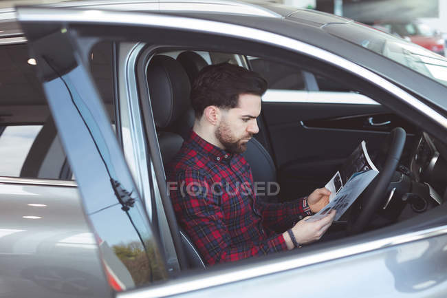 Продавець читання брошури всередині автомобіля в салоні — стокове фото