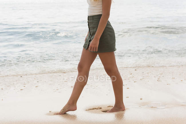 Baixa seção de mulher andando na praia em um dia ensolarado — Fotografia de Stock