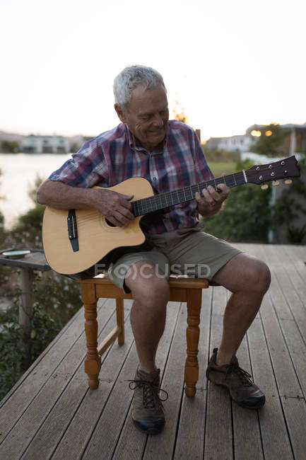 Senor man suonare la chitarra nel portico a casa — Foto stock