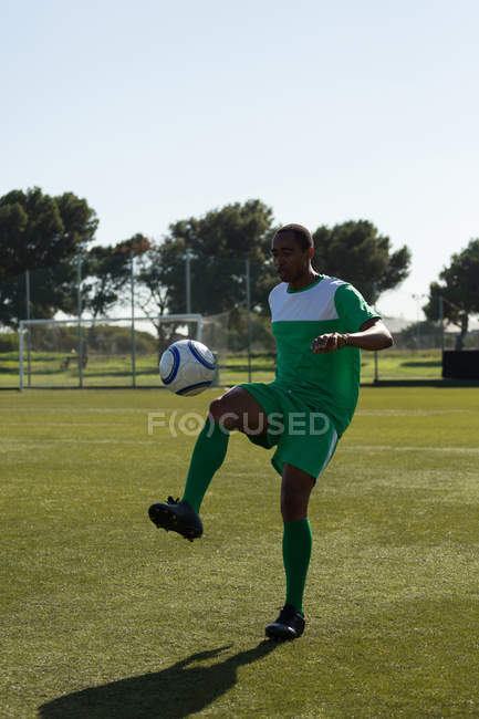 Joueur de football pratiquant avec un ballon sur le terrain — Photo de stock