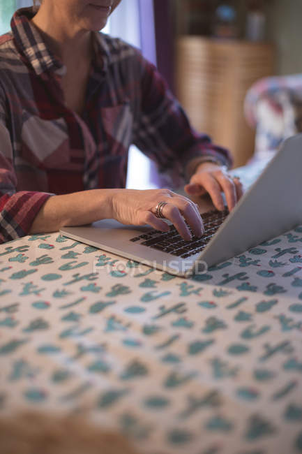 Mid section of woman using laptop on table at home — Stock Photo