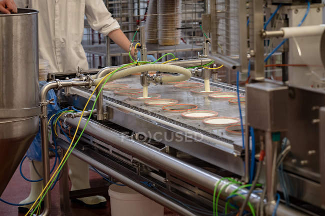 Section médiane du travailleur debout près de la ligne de production alimentaire dans l'usine — Photo de stock