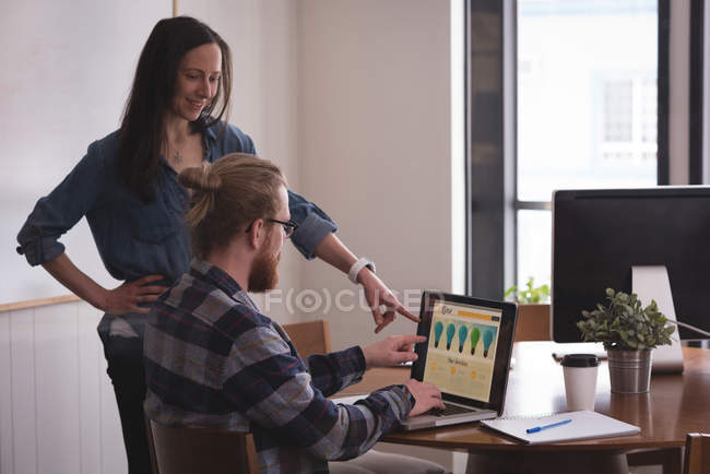 Geschäftskollegen diskutieren am Schreibtisch im Büro am Laptop — Stockfoto