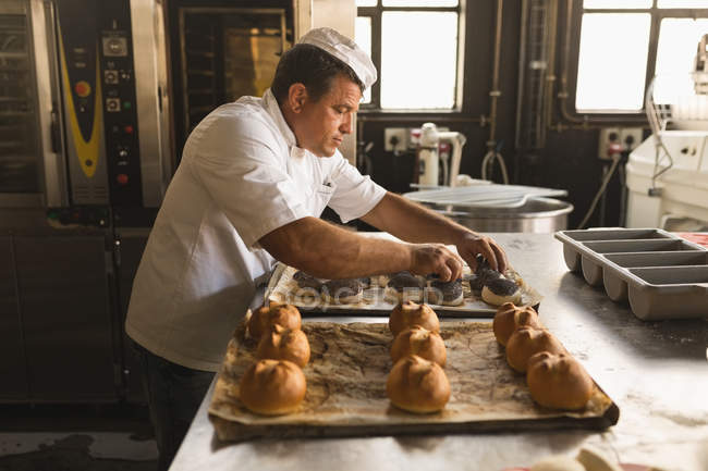 Чоловічий пекар готує круглі круасани в хлібобулочній майстерні — стокове фото