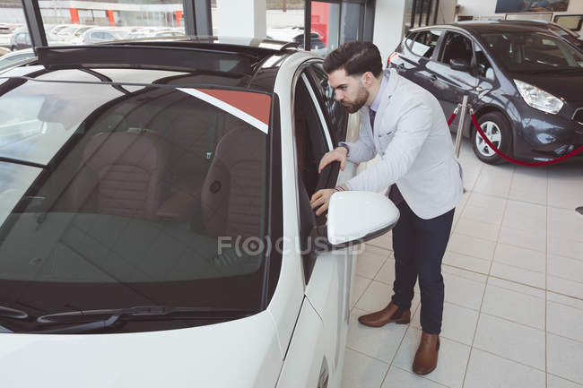 Schöner Verkäufer begutachtet Auto im Showroom — Stockfoto