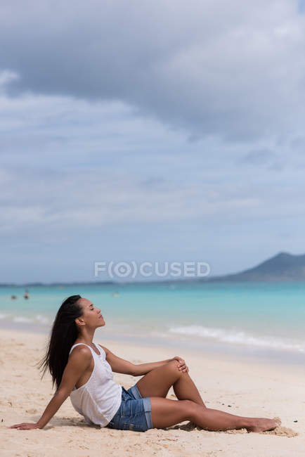 Jeune femme se relaxant à la plage — Photo de stock