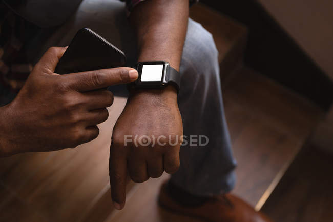 Progettista grafico senior utilizzando smartwatch alle scale in ufficio — Foto stock