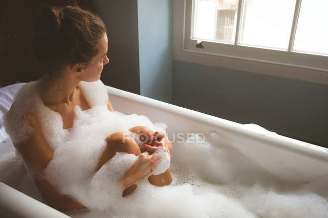 Woman taking a bubble bath in bathroom at home — Stock Photo