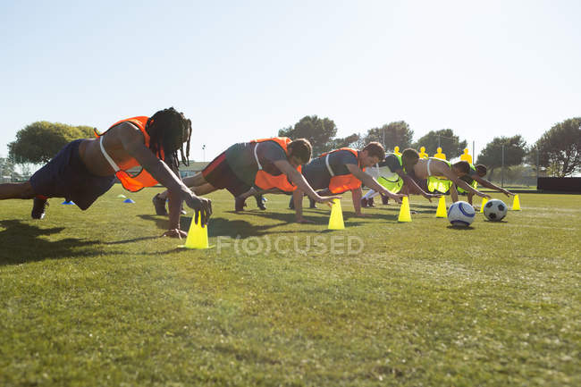 Jogadores que exercem com suporte de cone no campo — Fotografia de Stock
