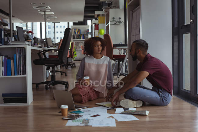 Arquitectos interactuando entre sí en el piso de la oficina - foto de stock