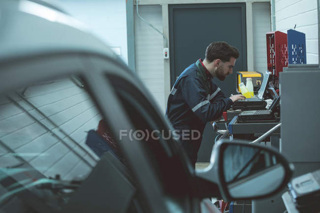 Mecânico atencioso usando laptop na garagem de reparação — Fotografia de Stock