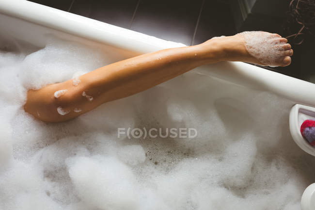 Donna gamba ricoperta di schiuma in bagno a casa — Foto stock