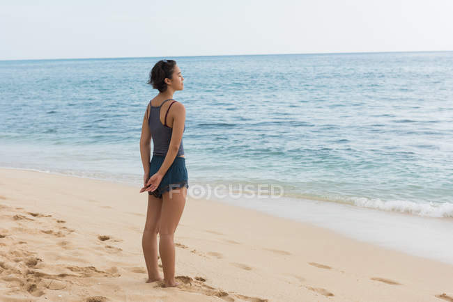 Beautiful woman standing with eyes closed in the beach — Stock Photo