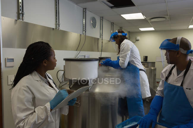 Scientists maintaining a record of medical sample on clipboard in lab — Stock Photo