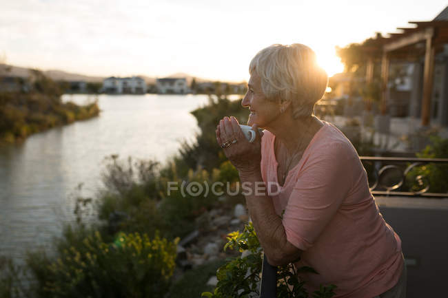Femme âgée prenant un café dans le balcon à la maison — Photo de stock