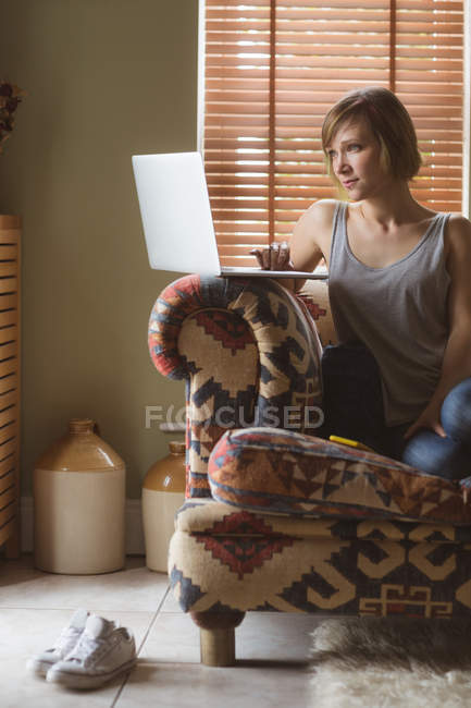 Красива жінка використовує ноутбук на дивані у вітальні вдома — стокове фото