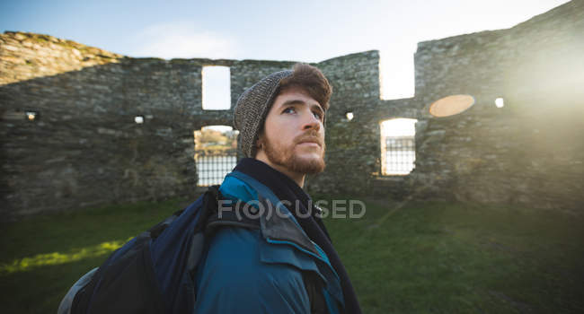 Jeune randonneur masculin debout dans la vieille ruine à la campagne — Photo de stock
