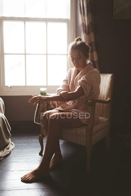 Красивая женщина применяет лосьон для тела дома — стоковое фото