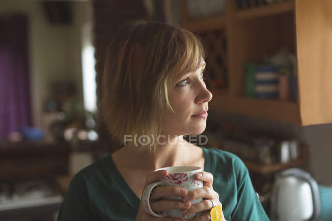 Крупним планом красива жінка має чашку кави вдома — стокове фото