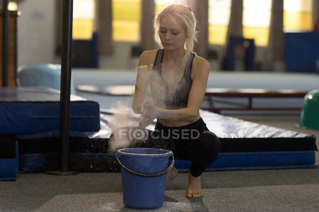 Sportswoman dusting her hands with chalk powder at fitness studio — Stock Photo