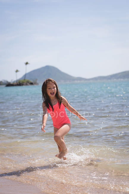 Menina brincando na água na praia em um dia ensolarado — Fotografia de Stock