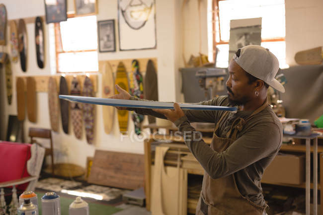 Man examining a skateboard in workshop — Stock Photo