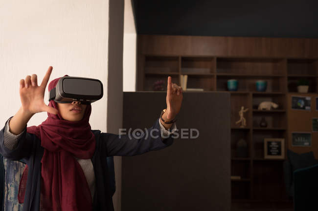 Empresária no hijab usando fone de ouvido de realidade virtual na cafetaria do escritório — Fotografia de Stock