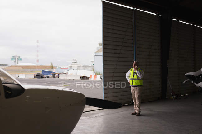 Un membre d'équipage parle sur son téléphone portable dans un hangar aérospatial — Photo de stock