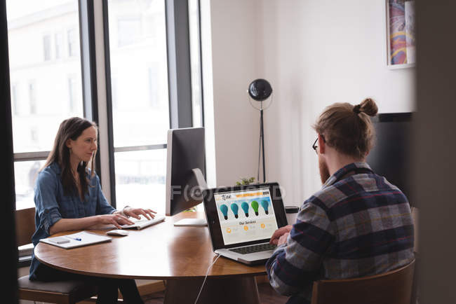 Ejecutivos masculinos y femeninos trabajando en el escritorio en la oficina - foto de stock
