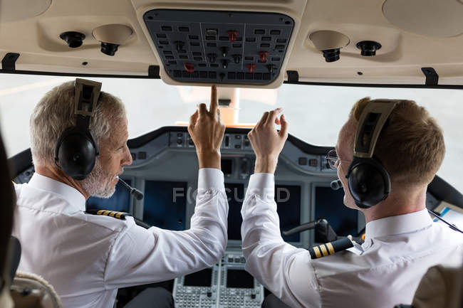 Two male pilots pushing button in private cockpit — Stock Photo