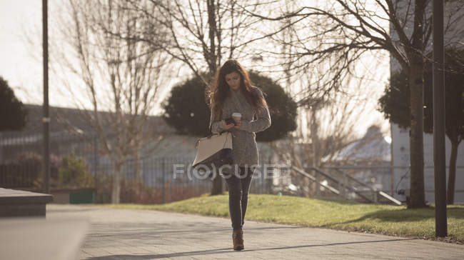 Молода жінка використовує мобільний телефон на міській вулиці — стокове фото