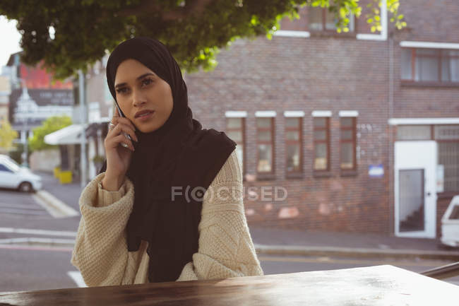 Beautiful urban hijab woman talking on mobile phone at cafe — Stock Photo