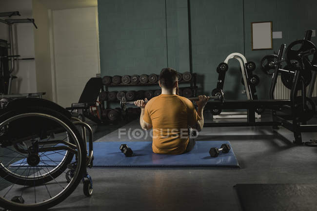Вид ззаду інвалідний чоловік займається з барбелом в тренажерному залі — стокове фото
