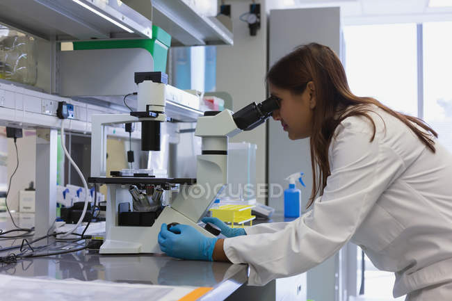 Female researcher analyzing samples with microscope in the laboratory — Stock Photo